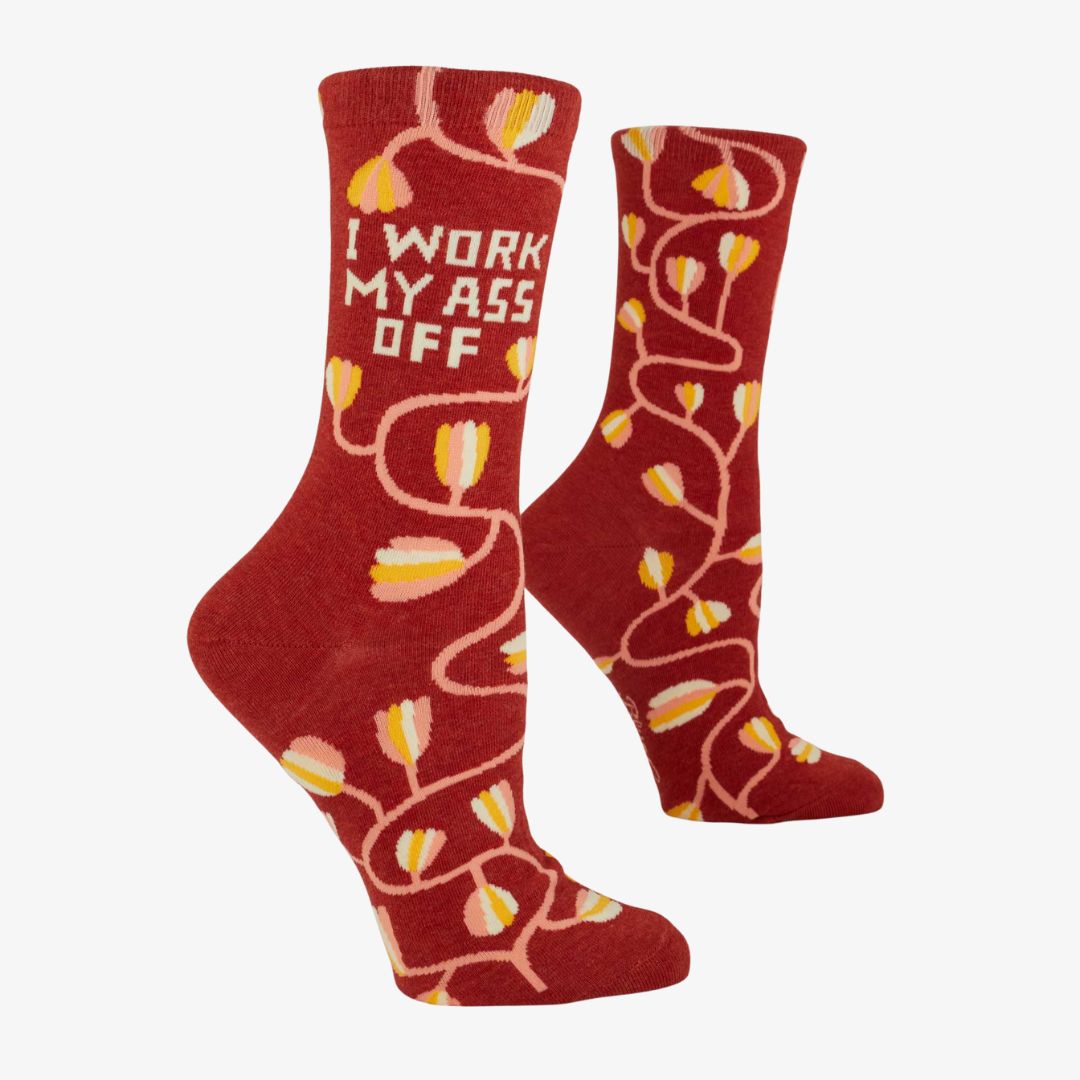 A pair of dark red women's crew socks with a winding vine pattern featuring yellow and pink tulip-shaped flowers. Text on one sock reads "I WORK MY ASS OFF".