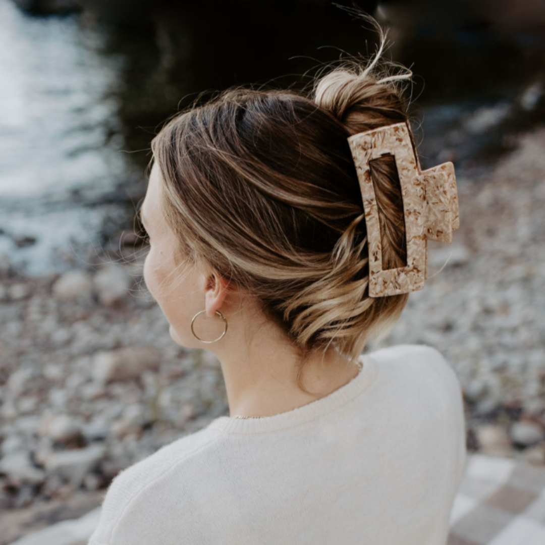 Woman with a decorative hair clip sitting by a body of water