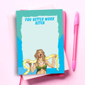 A humorous notepad featuring a cartoon of Britney Spears with a yellow python around her neck. The top of the notepad has the text "YOU BETTER WORK BITCH." The notepad is on a pink background with a pink pen.