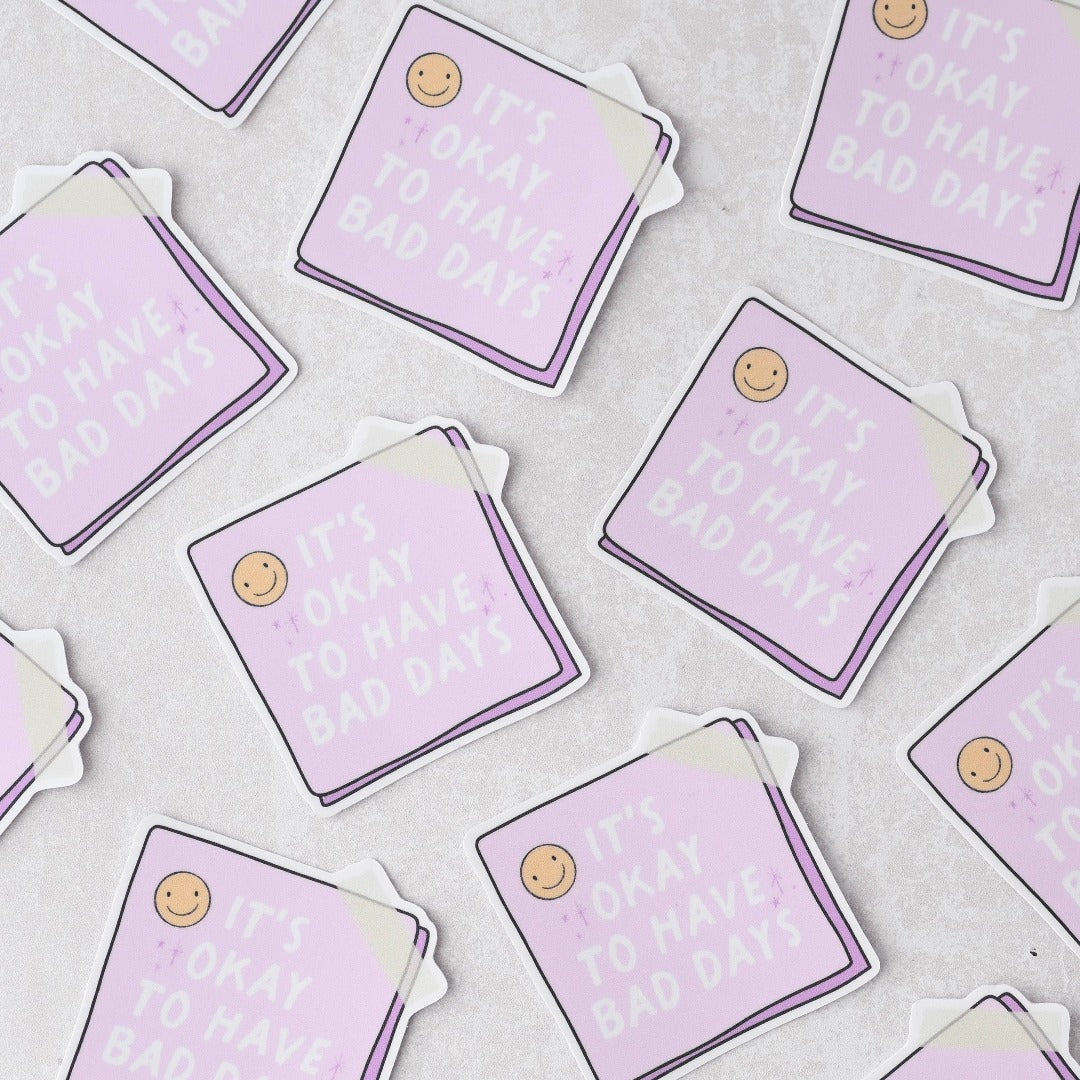 A bunch of It's Okay To Have Bad Days Sticker, a white sticker with a purple post it reading "It's okay to have bad days"