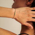 Person wearing a bracelet on their wrist with a neutral background