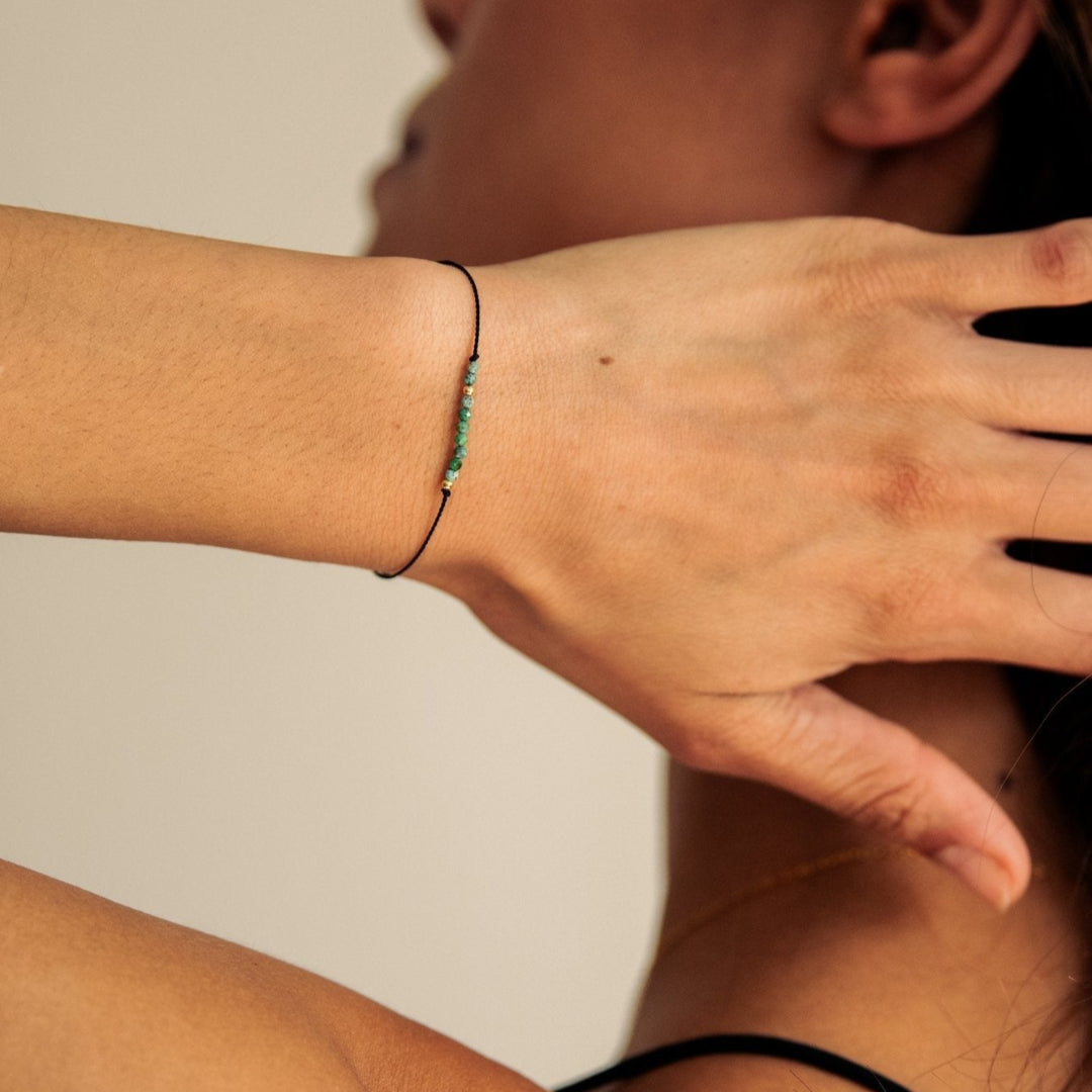 Person wearing a bracelet on their wrist with a neutral background