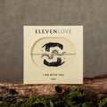 Card with 'Eleven Love' design on a wooden surface with moss