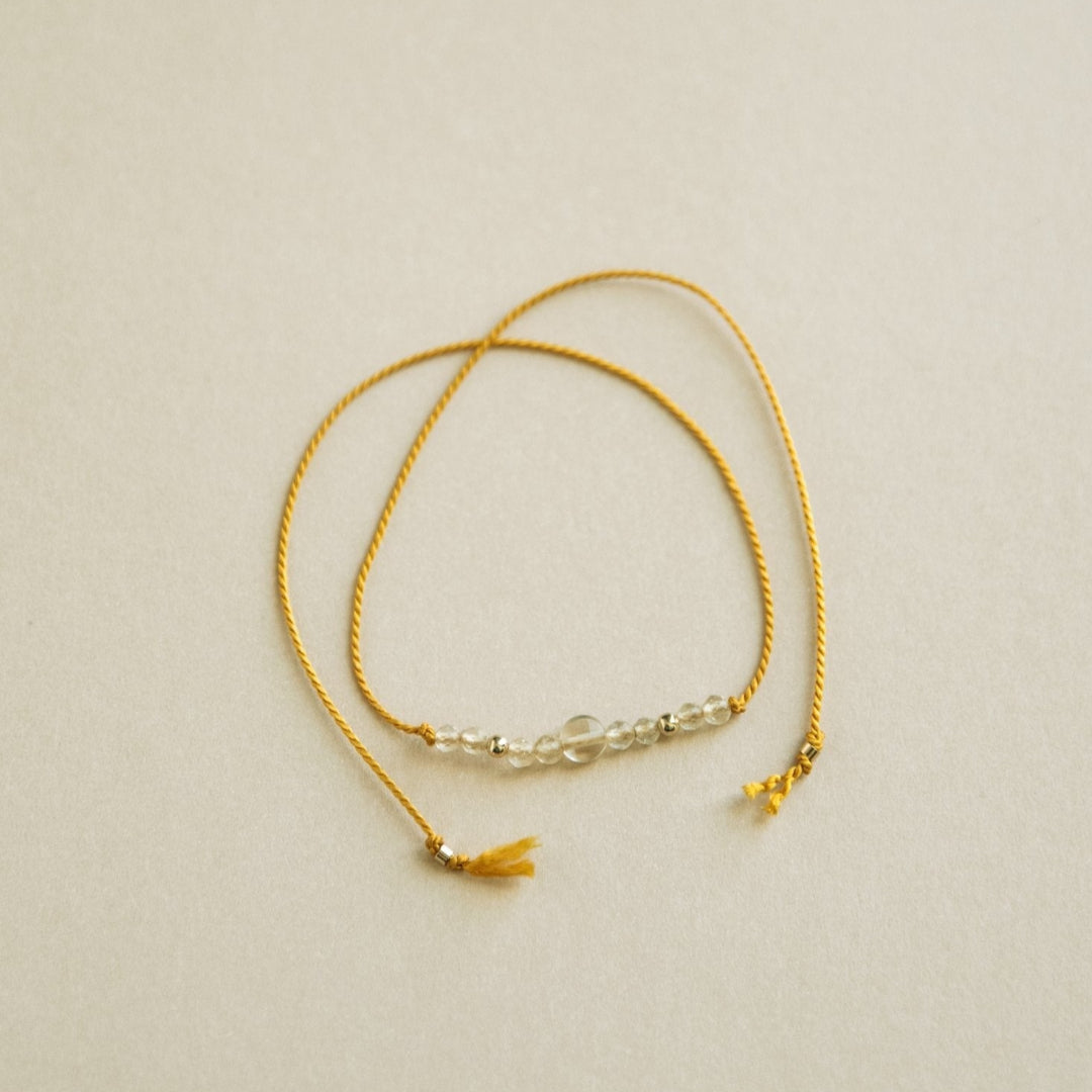 Gold bracelet with small beads on a beige background