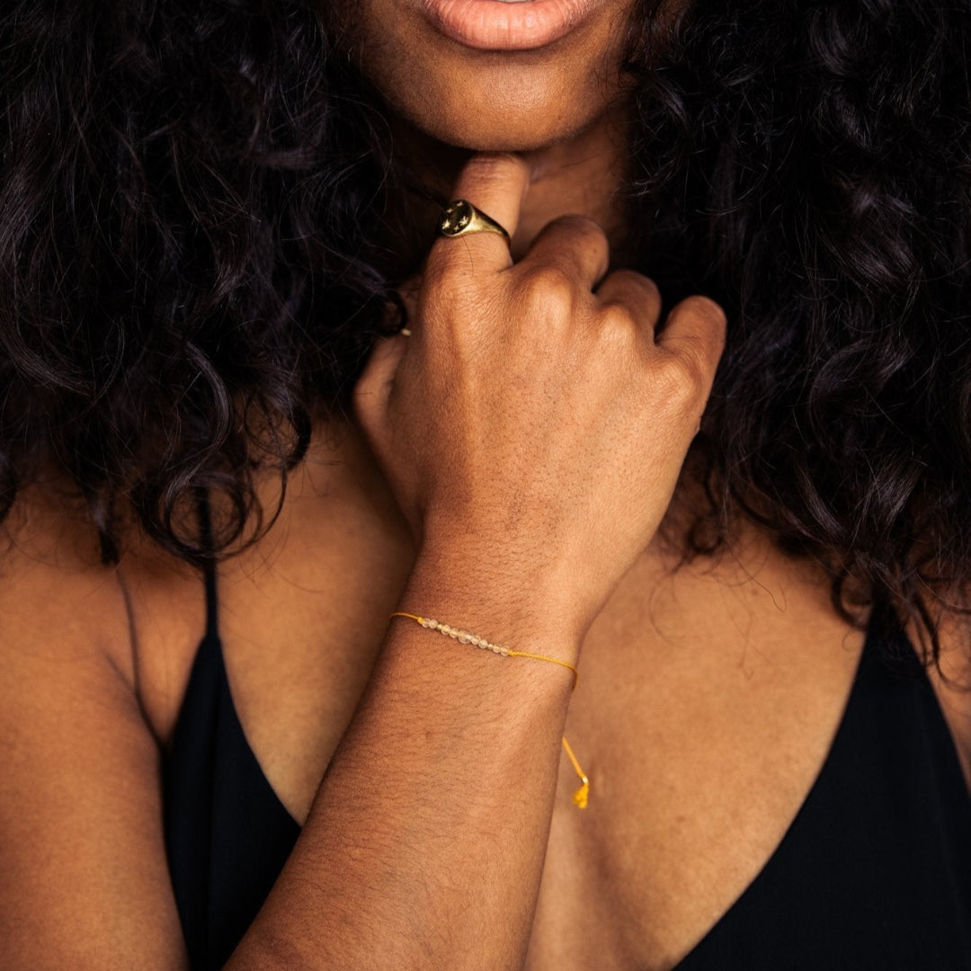 Woman with curly hair wearing a black tank top, looking directly at the camera.