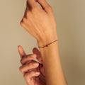 Close-up of two hands with a bracelet on a beige background