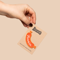 Hand holding a card with a foodie-themed badge on a beige background