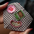 Checkered dog bandana with embroidered patches held by a hand