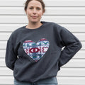 Person wearing a dark gray sweatshirt with a colorful heart design against a white background