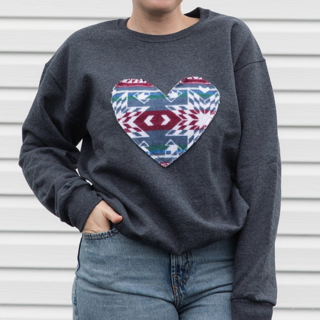 Person wearing a dark gray sweatshirt with a colorful heart design against a white background