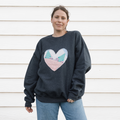 a grey sweatshirt with a large, heart-shaped patch. The patch is made from various fabrics with various patterns, sewn together in a patchwork style.
