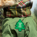 Green jacket with plaid collar and 'Trees are for Pees' patch on a blurred natural background
