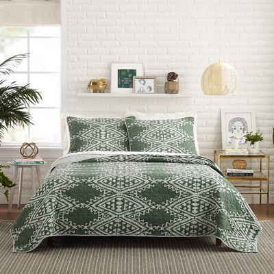 A bedroom with green and white quilt set.
