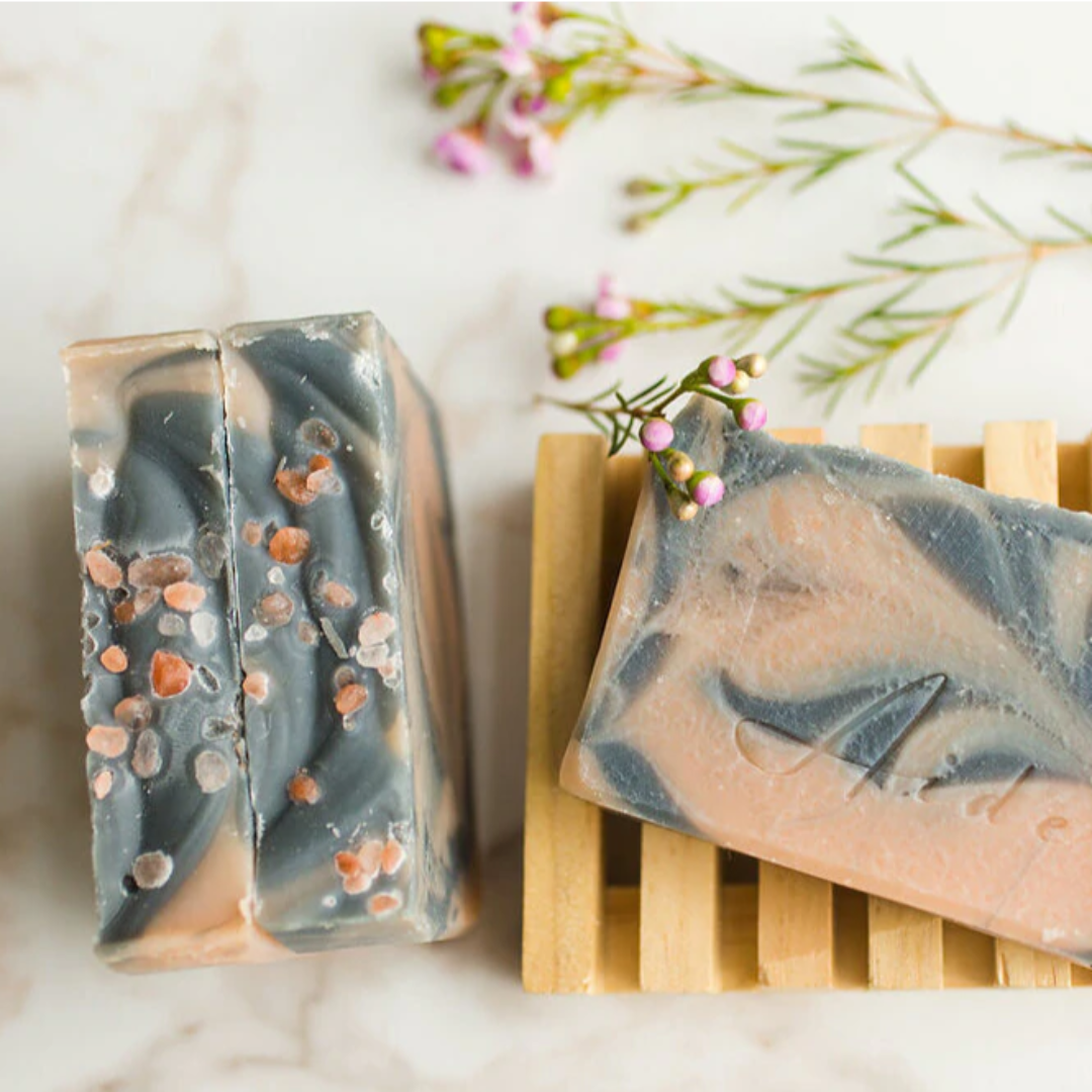 A bar of Aide Bodycare Salt & Surf Soap, featuring a light orange and dark gray swirled pattern and a paper label with the 'aide' logo and 'Salt & Surf' text, displayed on a light-colored surface with a shadow overlay. The soap is natural and handmade, available in Ottawa, Ontario, Canada.