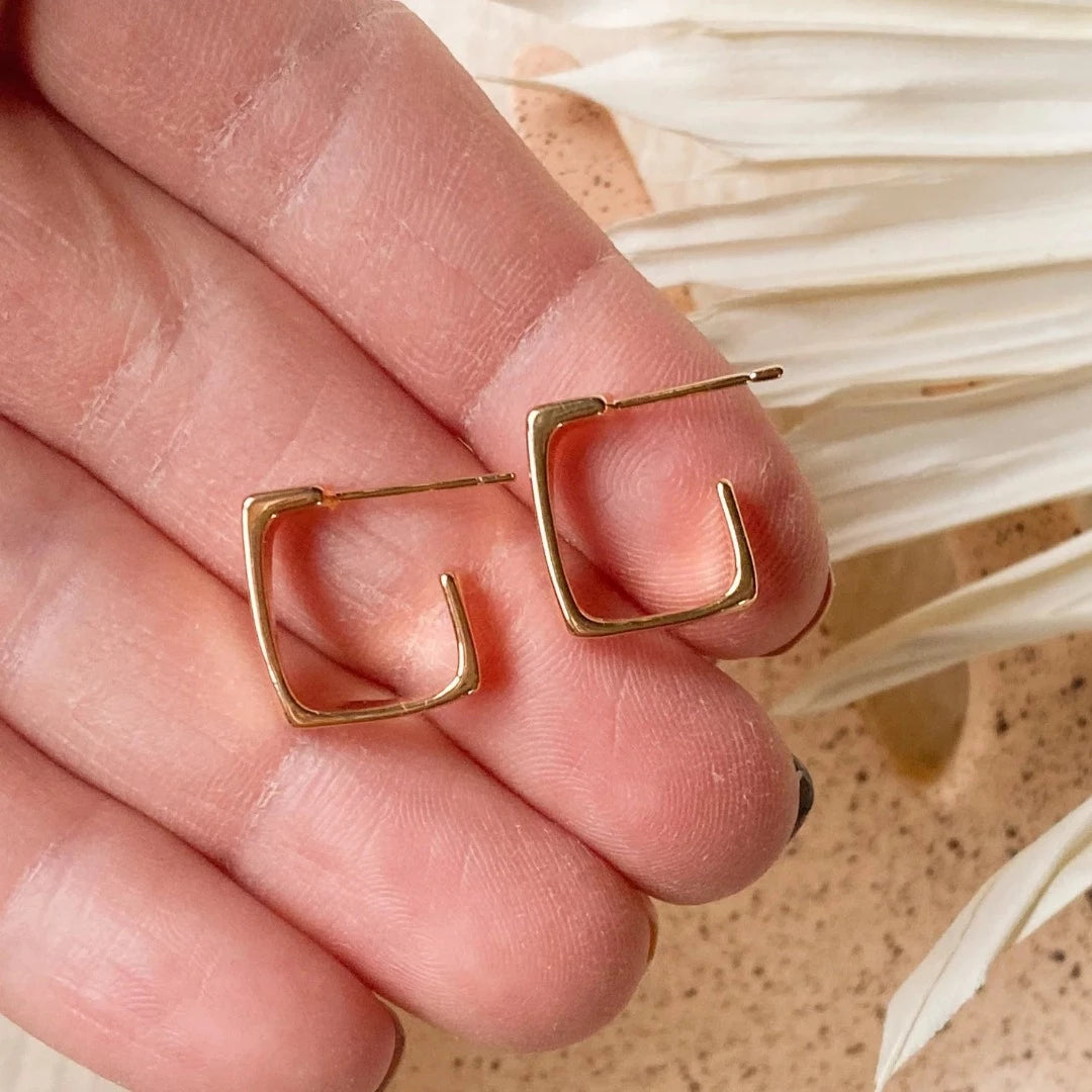 The Gold Squared Hoops are 18K gold plated with a stainless steel post that is nickel free Product close up held in hand