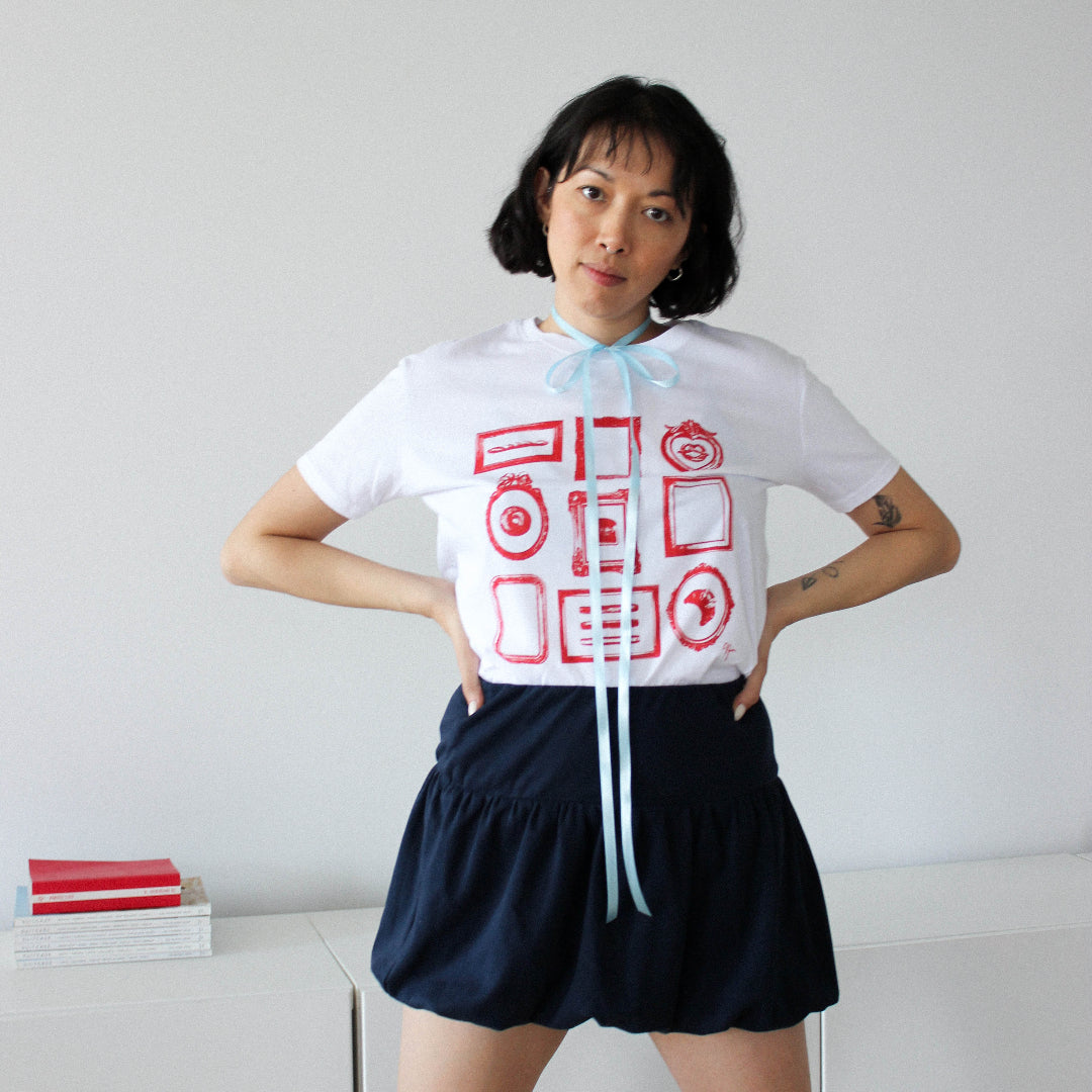 Person wearing a white t-shirt with red and blue graphics and black shorts against a plain background