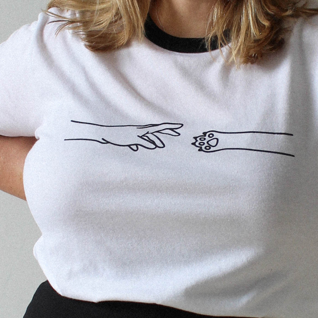 Person wearing a white t-shirt with black trim and a black skirt on a plain background