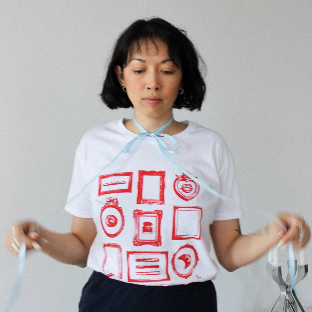 Person wearing a white t-shirt with red graphic design against a plain background