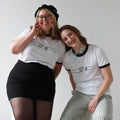Two people wearing matching white t-shirts with black designs against a plain background