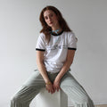 Person sitting on a white cube against a plain wall