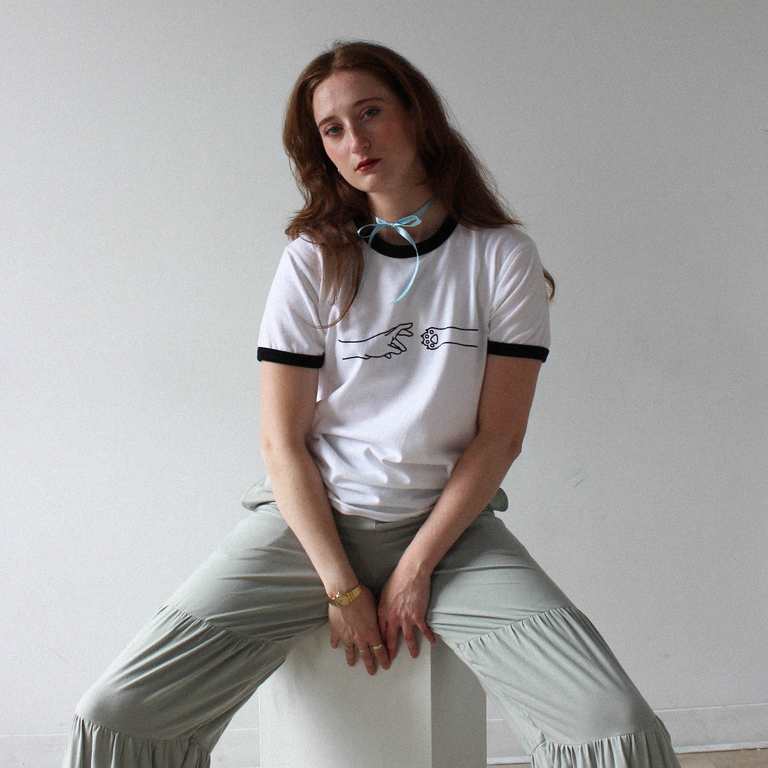 Person sitting on a white cube against a plain wall