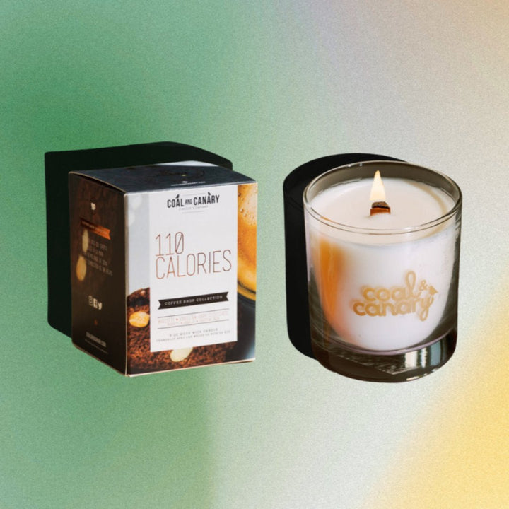 A white candle with a gold logo that says 