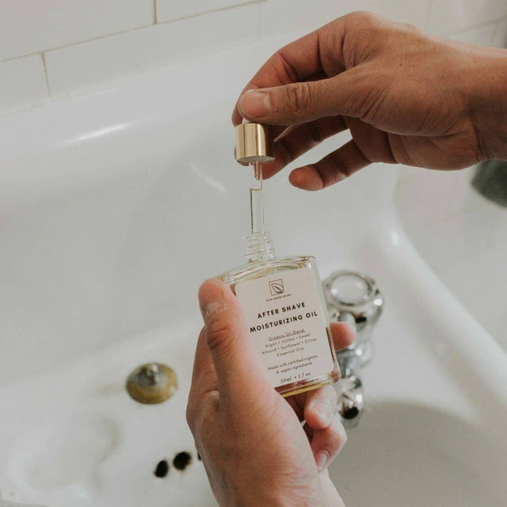 A glass dropper bottle filled with a clear, golden oil. The bottle has a black label with white text that reads 