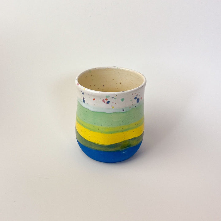 Peaceful Thumb Mug, a handless mug with a blue to green striped design and speckles finish.
