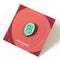 A mint green enamel pin in the shape of a speech bubble. The text 
