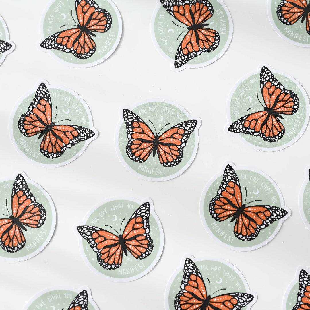 a bunch of You Are What You Manifest Sticker, a green sticker with a monarch butterfly in the middle with the words "You are what you Manifest" around it.