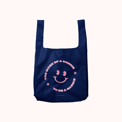 A navy blue, foldable tote bag with pink text and a smiley face. The text reads 