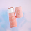 Sunset Glow Stick, a solid highlighter makeup stick in a warm coral pink sunset colour. It is presented in a cardboard tube, with a pull off top.