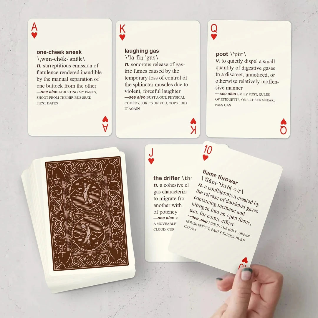 A deck of playing cards with a brown background and a cartoon illustration of a dog passing gas. The deck is enclosed in a cardboard box with the text "52 FARTS PLAYING CARDS" and "A Deck of Cards That Also Defines Every Type of Gas Ever Passed." The box also has the text "Know When to Hold 'Em - and When to Let 'Em Rip!"