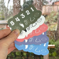 Stack of colorful stickers with various designs held by a hand outdoors.