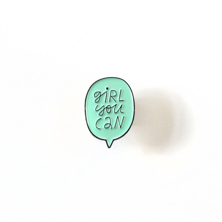A mint green enamel pin in the shape of a speech bubble. The text 