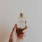 A glass dropper bottle filled with a clear, golden oil. The bottle has a black label with white text that reads 