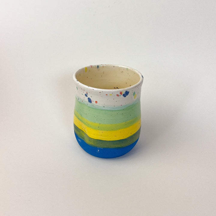 Peaceful Thumb Mug, a handless mug with a blue to green striped design and speckles finish.