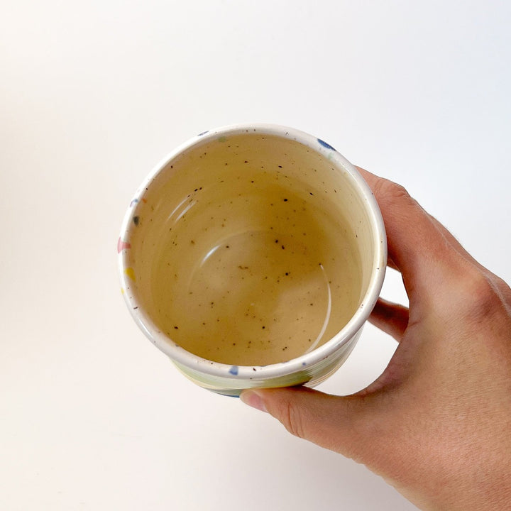 Peaceful Thumb Mug, a handless mug with a blue to green striped design and speckles finish.
