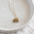 Gold necklace with acorn pendant on a textured white surface