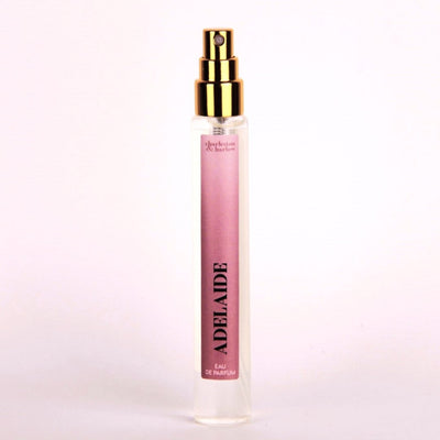 A small, clear glass perfume bottle with a gold cap and sprayer. The label reads 