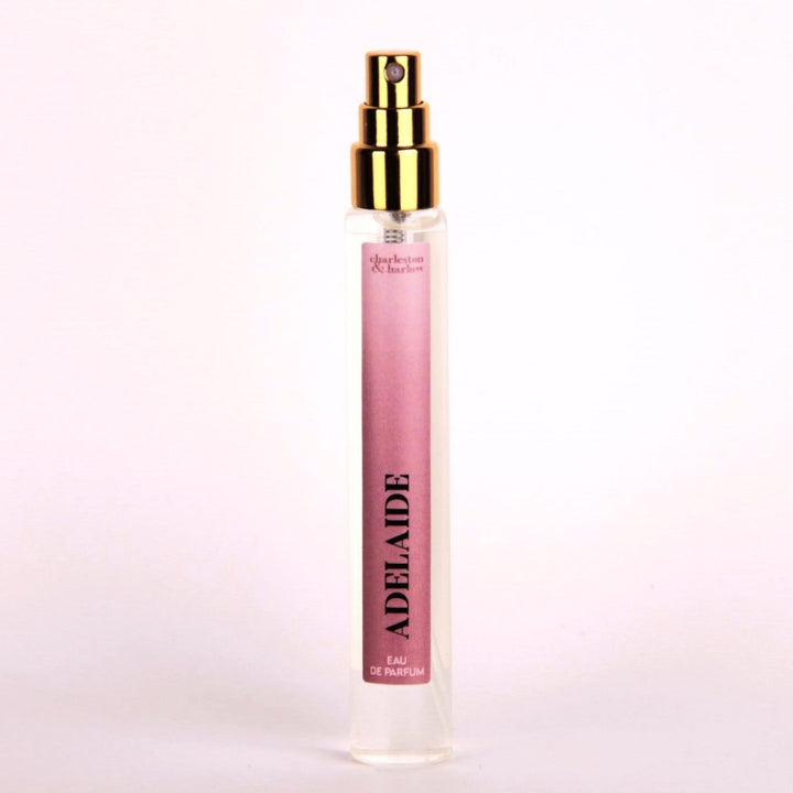 A small, clear glass perfume bottle with a gold cap and sprayer. The label reads 
