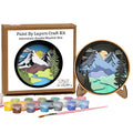 Paint by Layers Craft Kit for creating an Adventure Awaits Shadow Box, showing the kraft paper box packaging, a completed circular shadow box on a stand, a set of colorful paint pots, and a paintbrush on a white background.