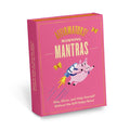 A pink box containing a deck of affirmation cards. The box has the text "AFFIRMATORS! MORNING MANTRAS" on the front. The cards have various affirmations printed on them, including "Rise, Shine, and Help Yourself Without the Self-Helpy-Ness!" and "Today is a piñata full of unknowns." The box also includes a small booklet with additional affirmations.
