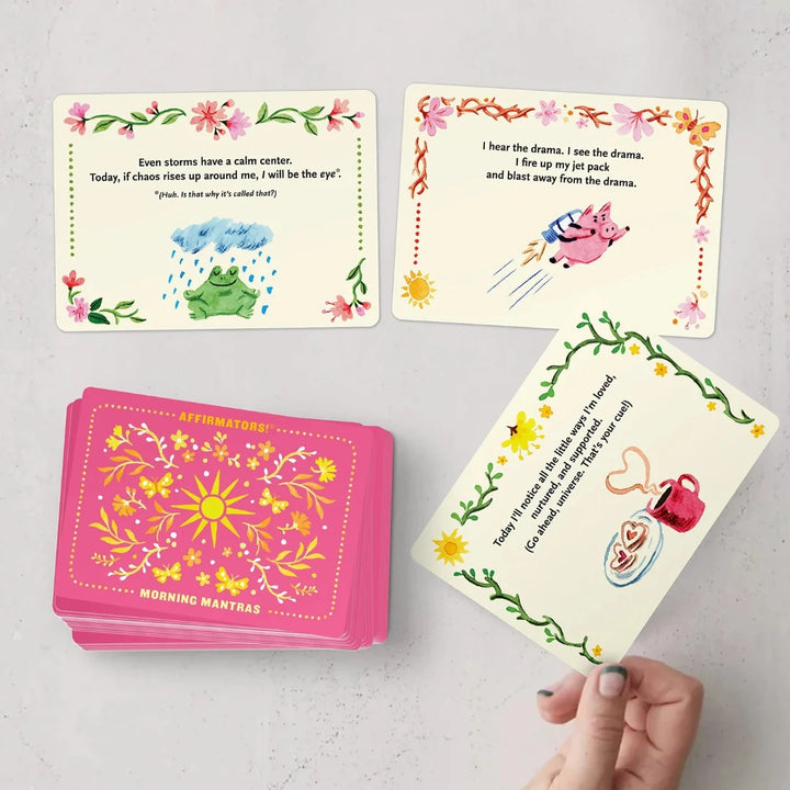 A pink box containing a deck of affirmation cards. The box has the text 