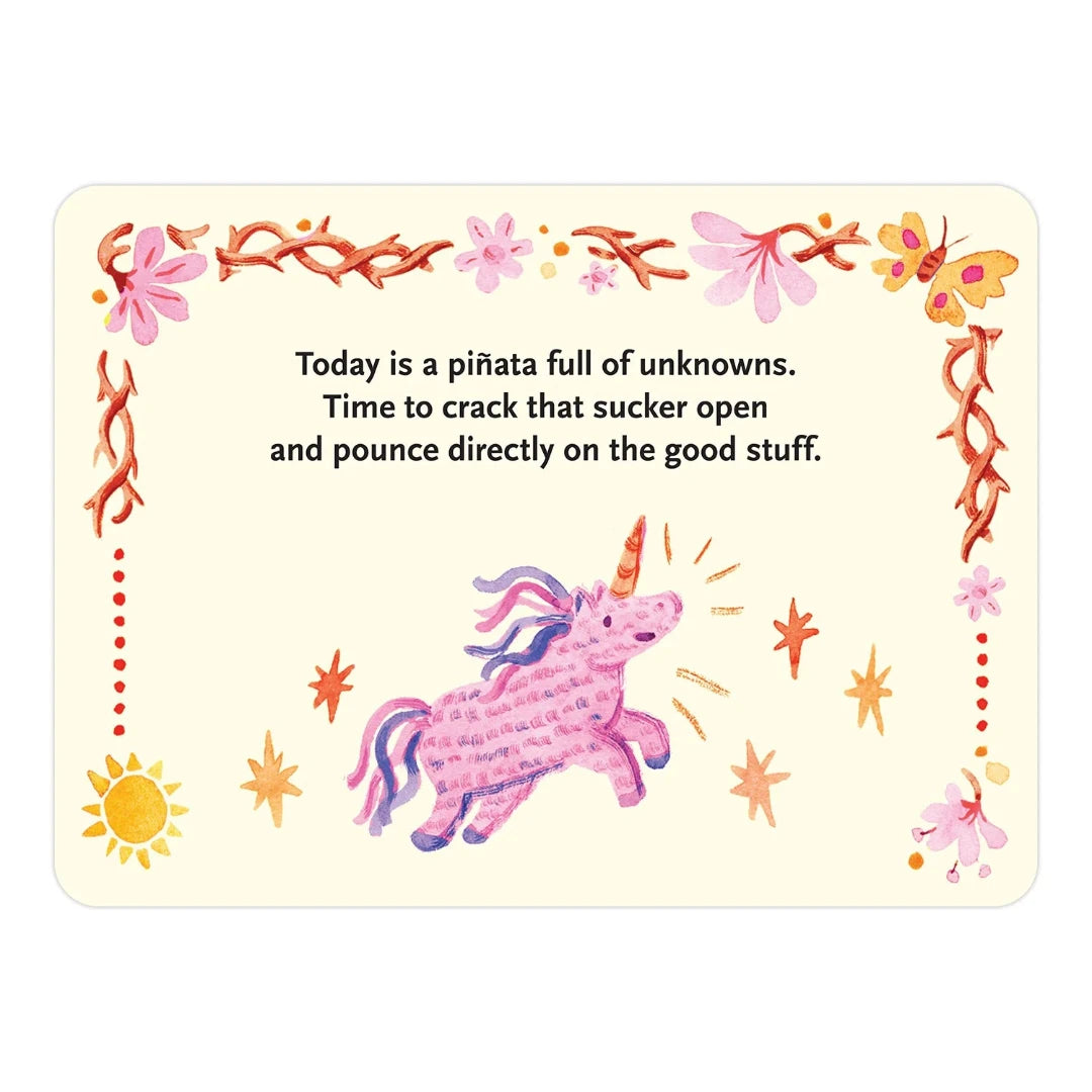 A pink box containing a deck of affirmation cards. The box has the text "AFFIRMATORS! MORNING MANTRAS" on the front. The cards have various affirmations printed on them, including "Rise, Shine, and Help Yourself Without the Self-Helpy-Ness!" and "Today is a piñata full of unknowns." The box also includes a small booklet with additional affirmations.