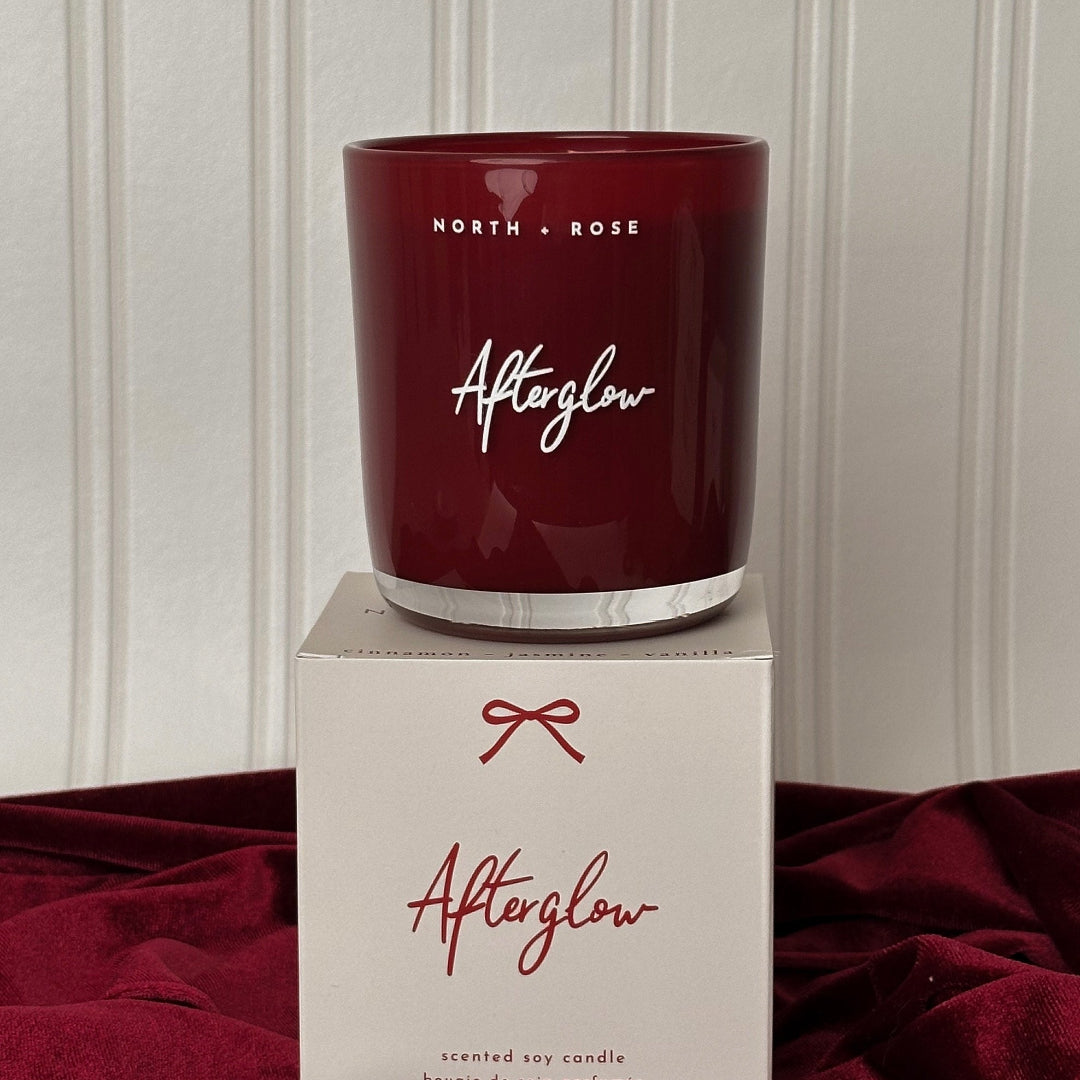 Red candle labeled 'Afterglow' by North & Rose on a matching box against a neutral background.
