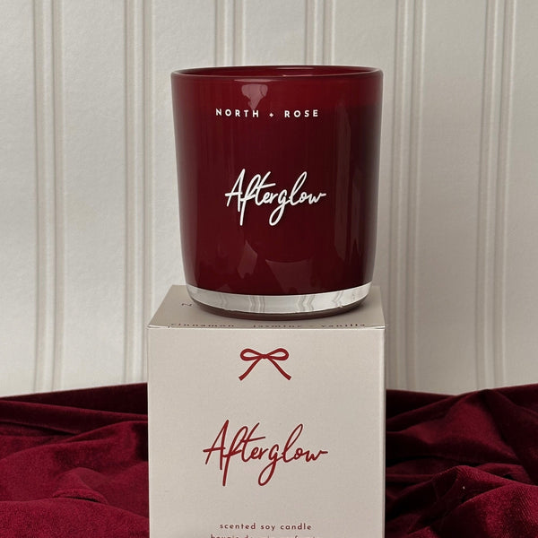 Red candle labeled 'Afterglow' by North & Rose on a matching box against a neutral background.