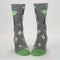 A pair of men's crew socks with a grey background and a pattern of white starbursts and green accents. One sock features the rear end of a white donkey and the text 