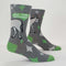 A pair of men's crew socks with a grey background and a pattern of white starbursts and green accents. One sock features the rear end of a white donkey and the text 