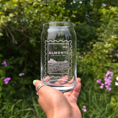 Clear glass with 'Almonte' branding held in front of a green, leafy background